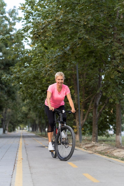 Mulher madura sorridente andando de bicicleta ao ar livre