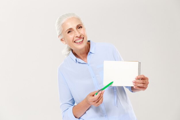 Mulher madura sorridente, mostrando o caderno com espaço de cópia para texto isolado