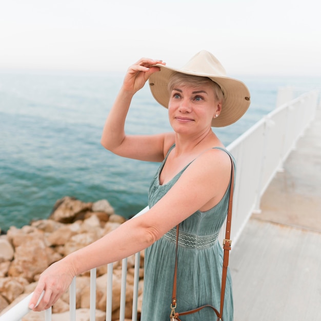 Mulher mais velha do turista na praia com chapéu