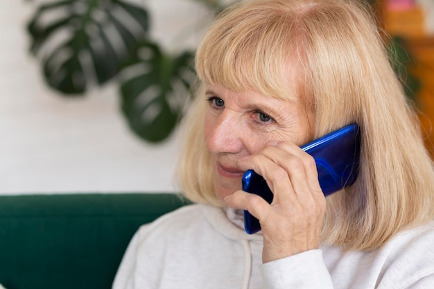 Mulher mais velha falando ao telefone em casa