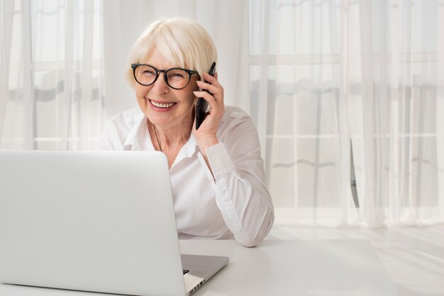 Mulher mais velha sorridente, falando ao telefone