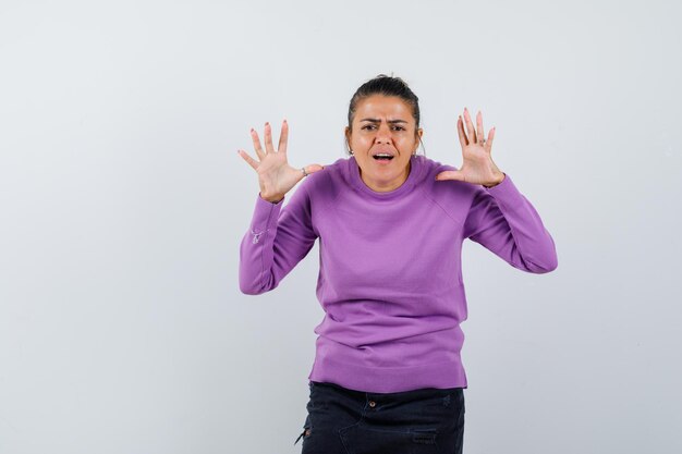 Mulher mantendo as mãos levantadas, tendo problemas para ouvir em uma blusa de lã e parecendo confusa