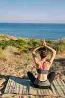 Foto grátis mulher meditando na vista traseira da praia