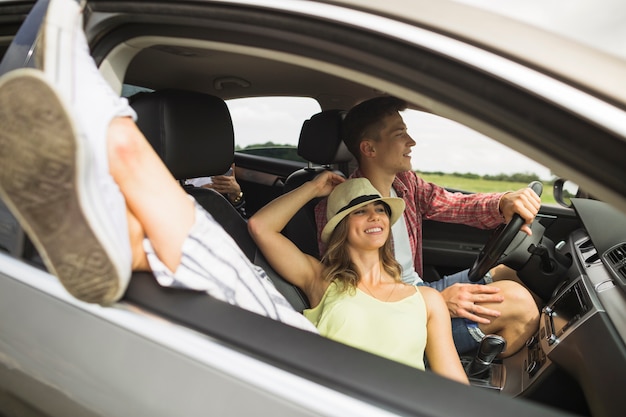 Mulher, mentindo carro, com, dela, pés, saída, de, janela carro, com, seu, namorado, dirigindo