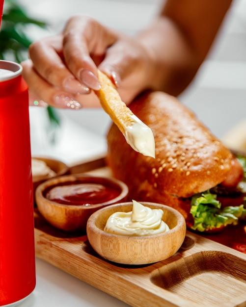 Mulher mergulha batatas fritas em maionese