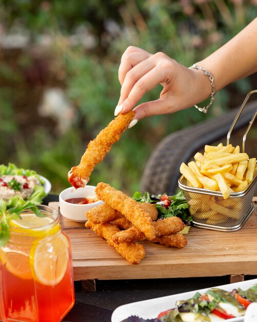 Mulher mergulhando croquetes de dedo de galinha em ketchup