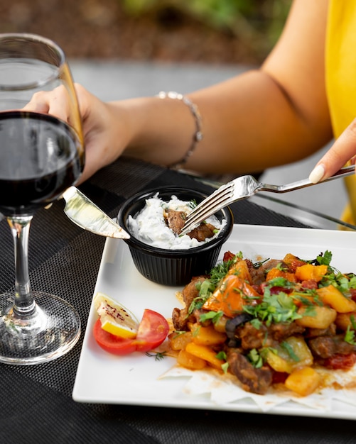 Foto grátis mulher mergulhando o cubo de carne em molho de molho com iogurte e ervas