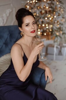 Mulher modelo com uma taça de champanhe na festa de ano novo, bebendo champanhe no feriado festivo ligh ...