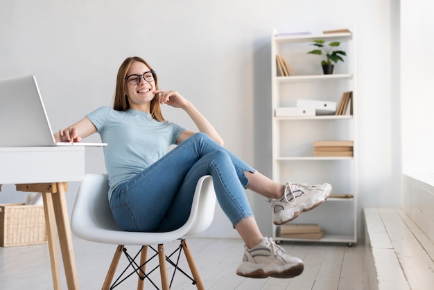 Foto grátis mulher moderna de longo tiro relaxante na cadeira dela