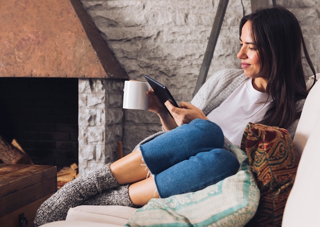 Mulher moderna sentada no sofá usando um tablet