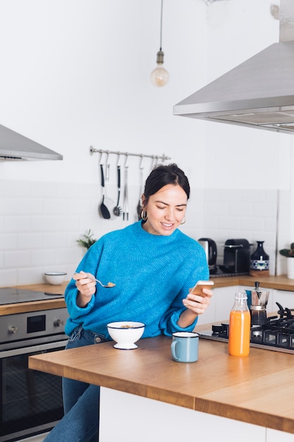 Mulher moderna tomando café da manhã na cozinha