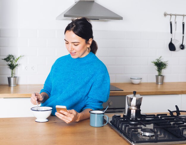 Mulher moderna tomando café da manhã na cozinha