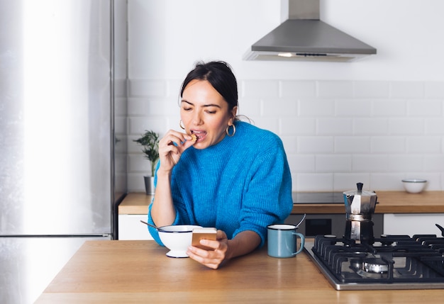 Mulher moderna tomando café da manhã na cozinha