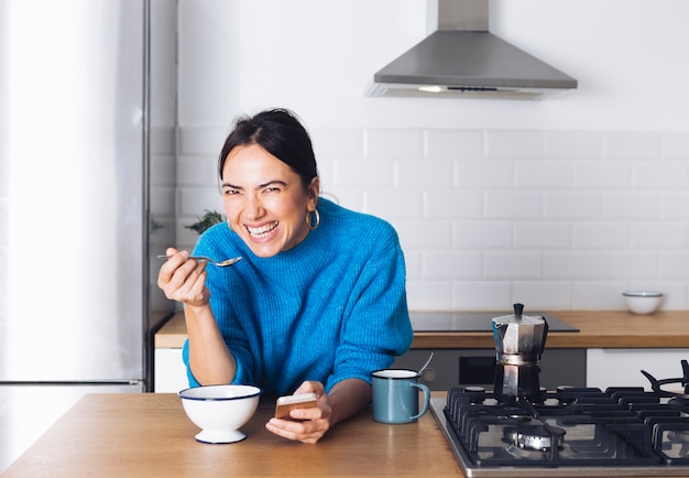 Mulher moderna tomando café da manhã na cozinha