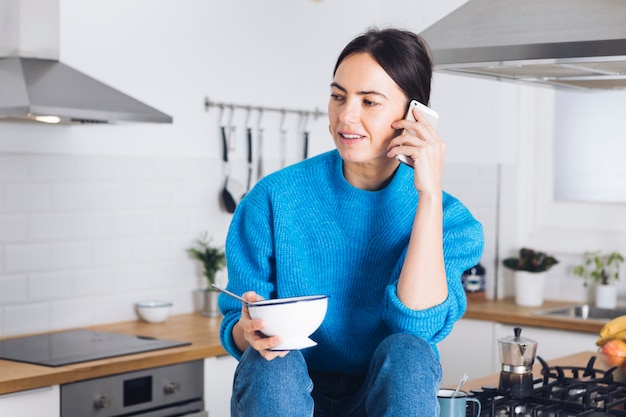 Mulher moderna tomando café da manhã na cozinha