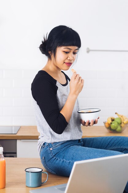 Mulher moderna tomando café da manhã na cozinha