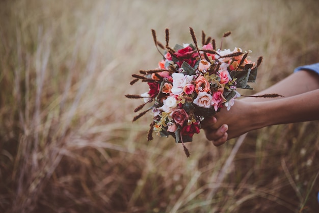 Mulher moderno jovem segurando buquê de rosas enquanto desfrutar de um passeio no campo do verão.