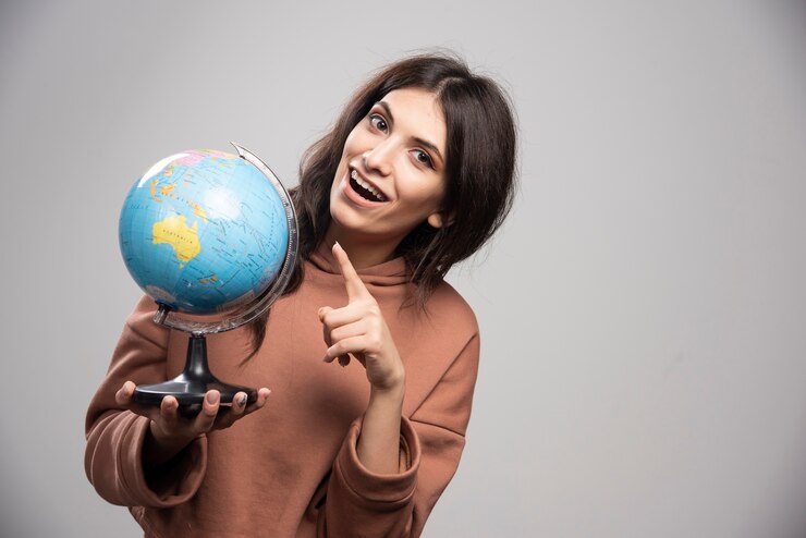 Foto grátis mulher morena apontando para o globo em cinza