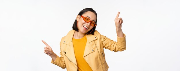 Mulher morena asiática sorridente em óculos de sol apontando os dedos para o lado esquerdo e direito mostrando variantes