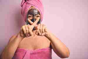 Foto grátis mulher morena de meia-idade usando beleza máscara facial preta sobre fundo rosa isolado expressão de rejeição cruzando os dedos fazendo sinal negativo