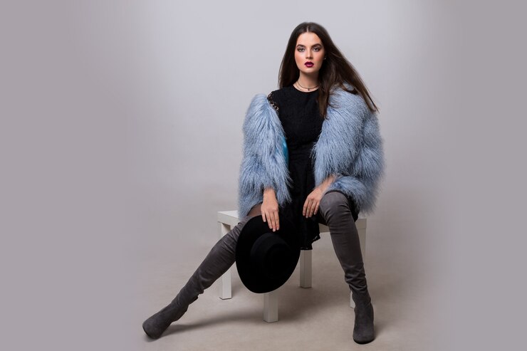 Foto grátis mulher morena sexy na jaqueta de pele azul da moda e botas altas de veludo thight, posando na parede cinza.