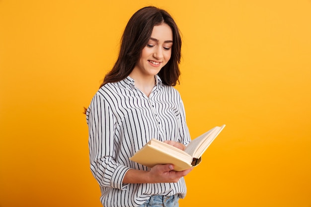 Mulher morena sorridente na camisa lendo livro