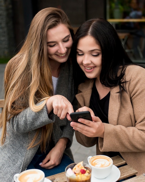 Foto grátis mulher mostrando algo em seu telefone para uma amiga