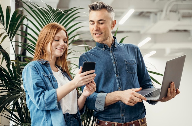 Foto grátis mulher mostrando algo em um telefone para seu colega de trabalho