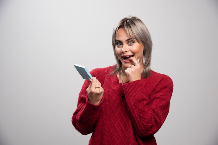 Foto grátis mulher mostrando bloco de notas e rindo sobre fundo cinza.