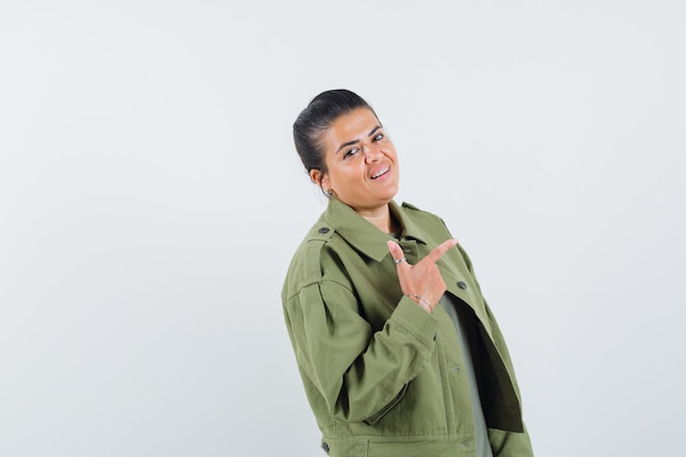mulher mostrando gesto de arma em jaqueta, camiseta e parecendo confiante