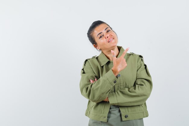 Mulher mostrando gesto de arma em jaqueta, camiseta e parecendo confiante