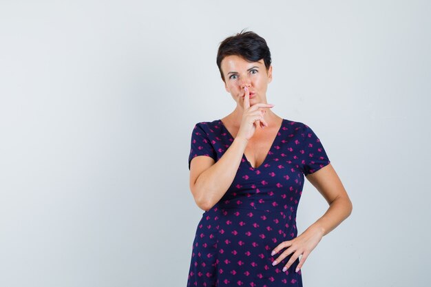 Mulher mostrando gesto de silêncio no vestido e olhando cuidadoso.