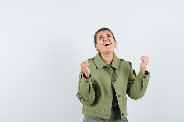 mulher mostrando gesto de vencedor com jaqueta, camiseta e parecendo feliz