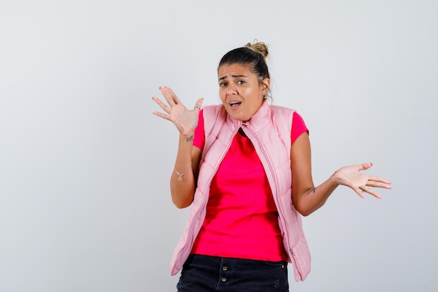 Mulher mostrando gesto desamparado em camiseta, colete e parecendo confusa