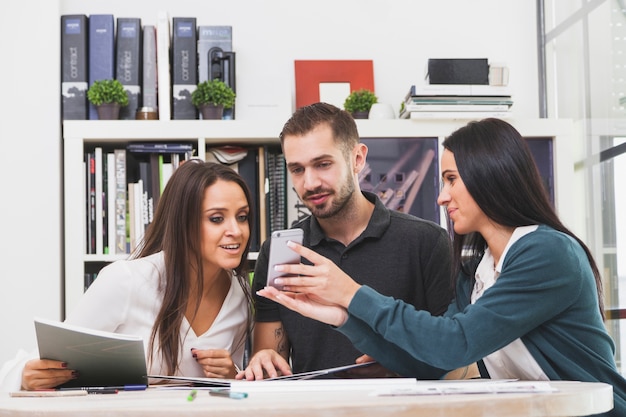 Mulher mostrando smartphone para colegas