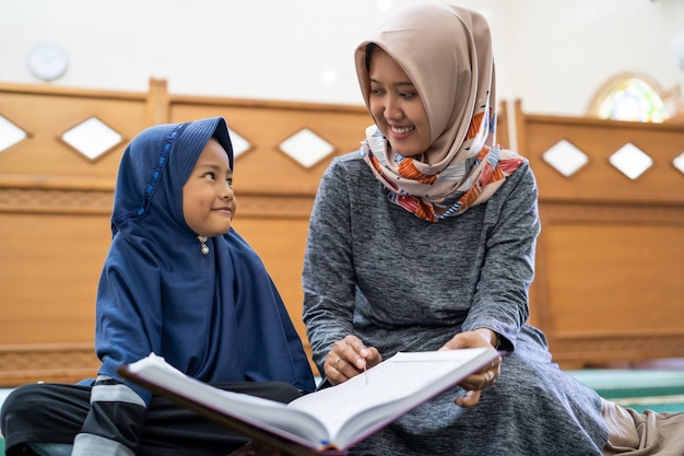 Mulher muçulmana com crianças lendo o alcorão juntos