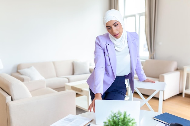 Mulher muçulmana trabalhando com computador em casa Mulher muçulmana trabalhando com computador na sala escrevendo papel Confiança mulher muçulmana bonita Conceitos de negócios e finanças