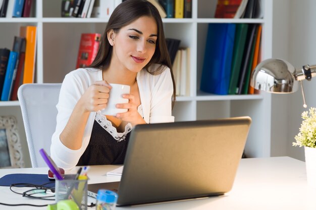 Mulher muito jovem trabalhando com laptop em seu escritório.