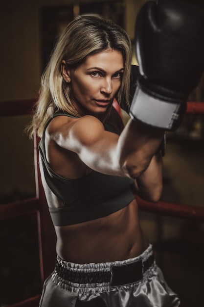 Mulher muscular focada tem seu treinamento de boxe usando luvas de boxe.