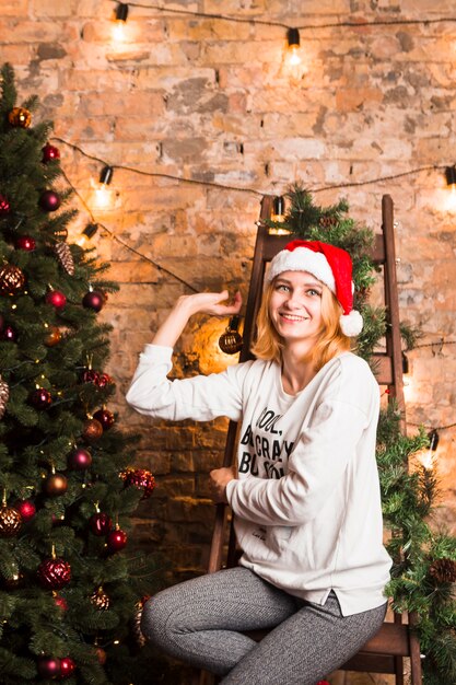 Foto grátis mulher na cadeira ao lado da árvore de natal