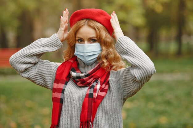 Mulher na floresta de outono. pessoa com máscara. tema coronavirus. senhora em um lenço vermelho.