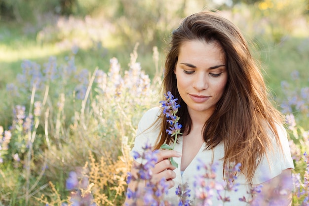 Mulher na natureza posando ao lado de lindas flores