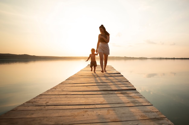 Foto grátis mulher na praia com seu bebê aproveitando o pôr do sol