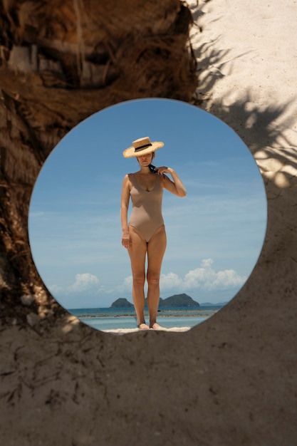 Mulher na praia no verão posando com espelho redondo