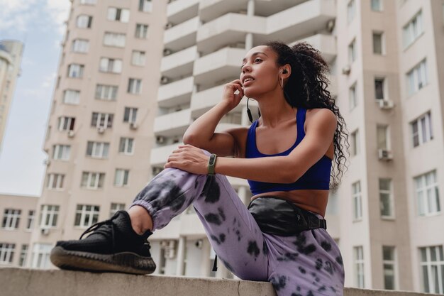 Mulher negra afro-americana atraente em roupa de ginástica esportiva no telhado fazendo exercícios