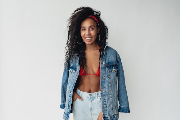 Mulher negra afro-americana em roupa elegante hipster jaqueta jeans e jeans branco