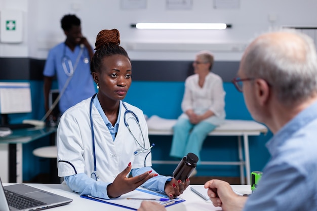 Mulher negra com profissão médica segurando um frasco de comprimidos