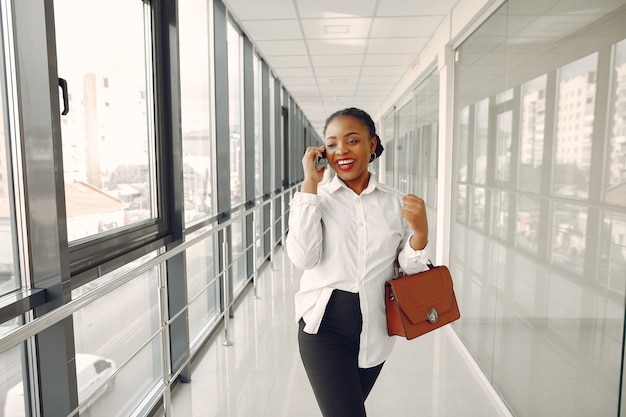 Mulher negra em pé no escritório com um laptop