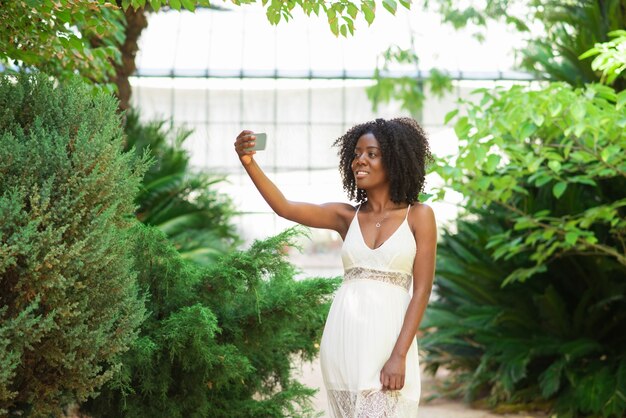Mulher negra positiva que tira foto de Selfie no parque