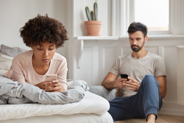 Mulher negra relaxada em blogs via aplicativo, deitada na cama